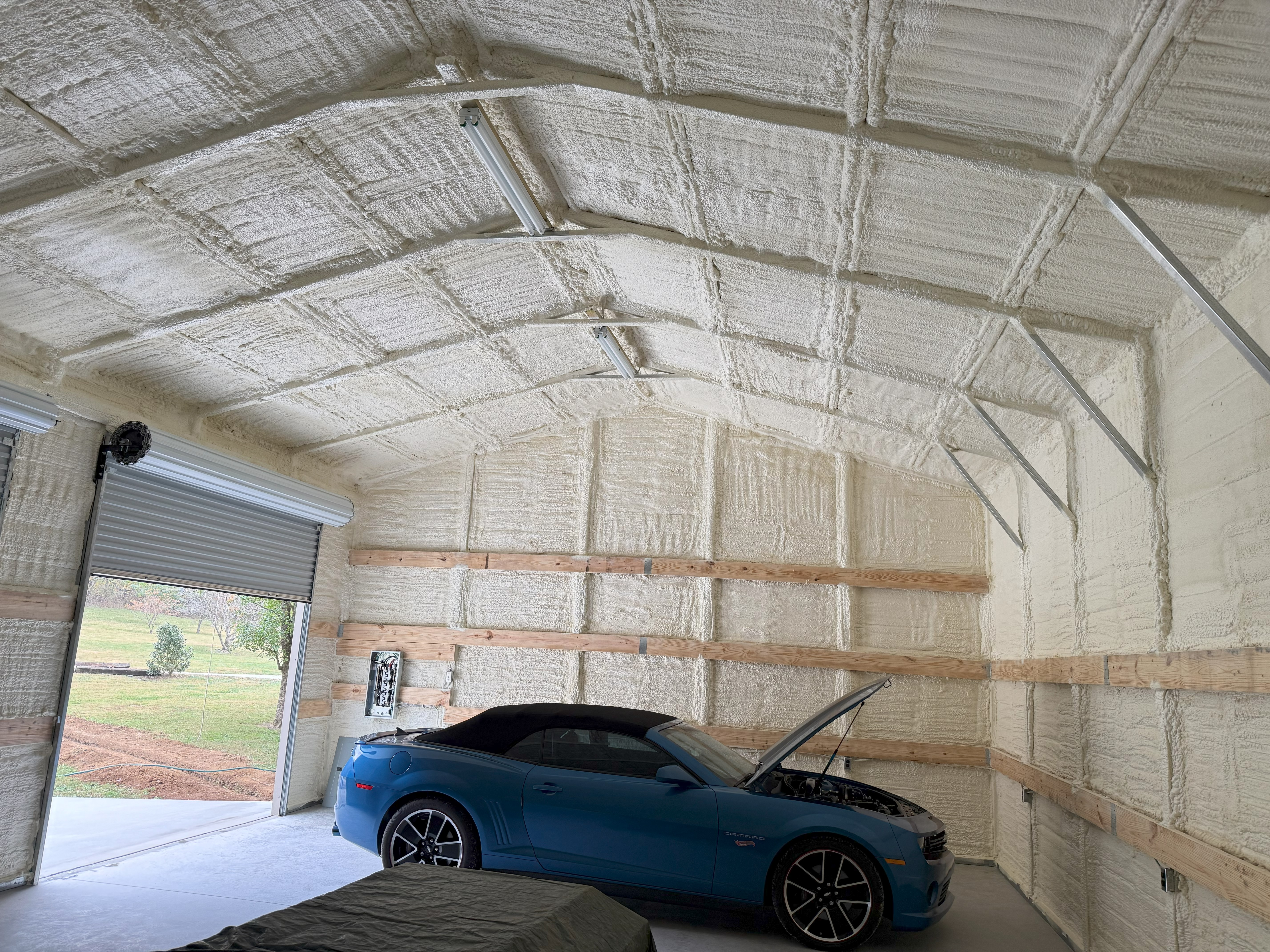 Spray foam insulation installed inside a garage project with exposed framing.