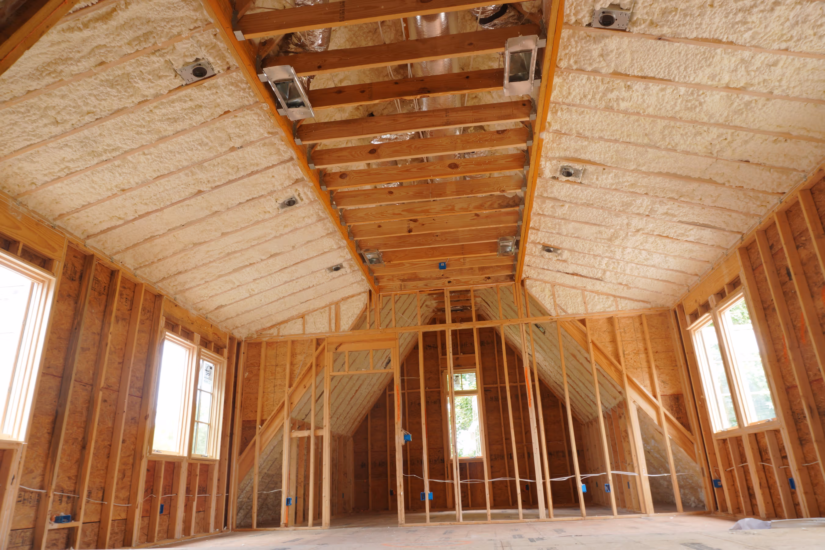 Wide jobsite view of spray foam insulation applied through a large attic cavity.
