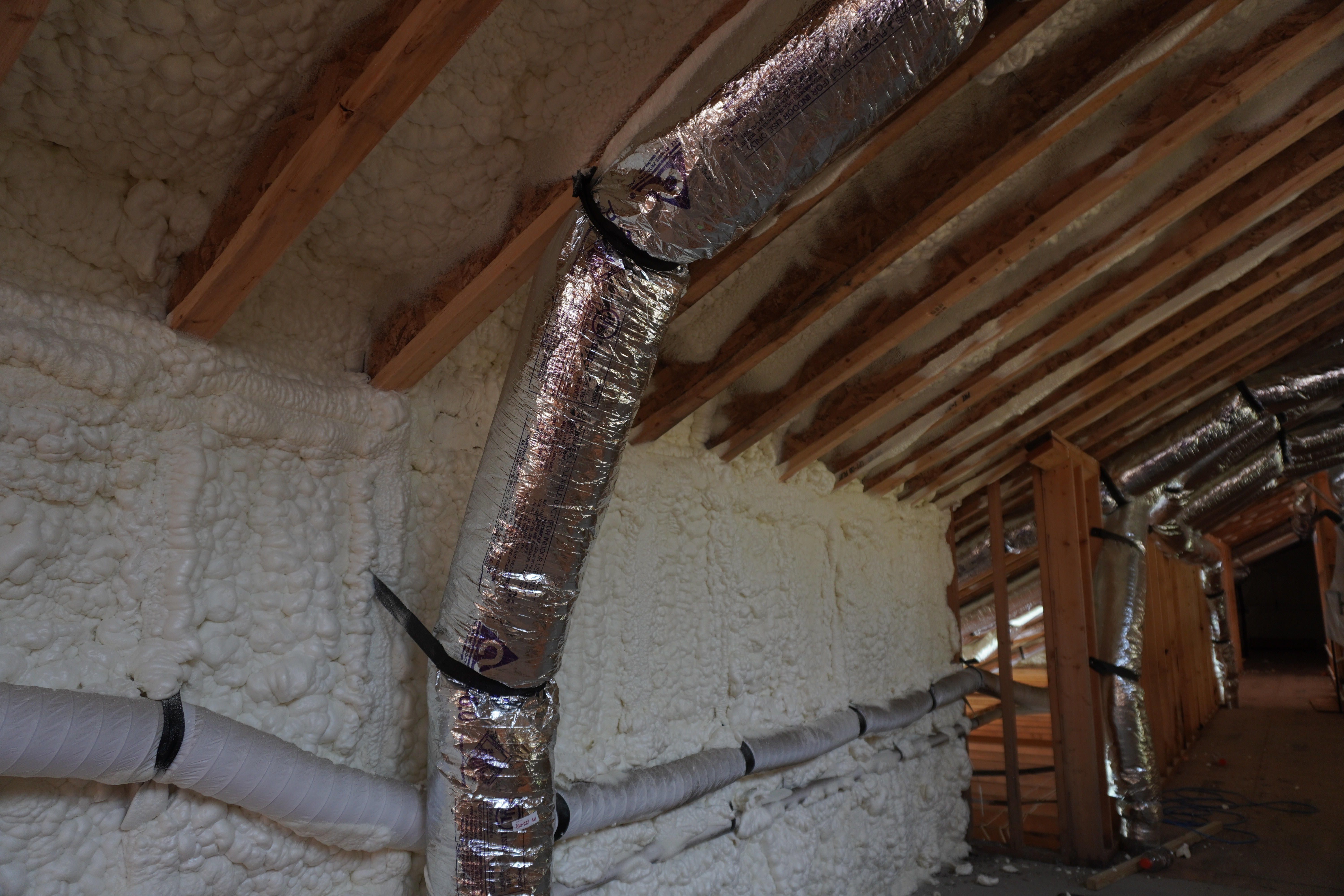 Spray foam installed across wall cavities and sloped roof framing.