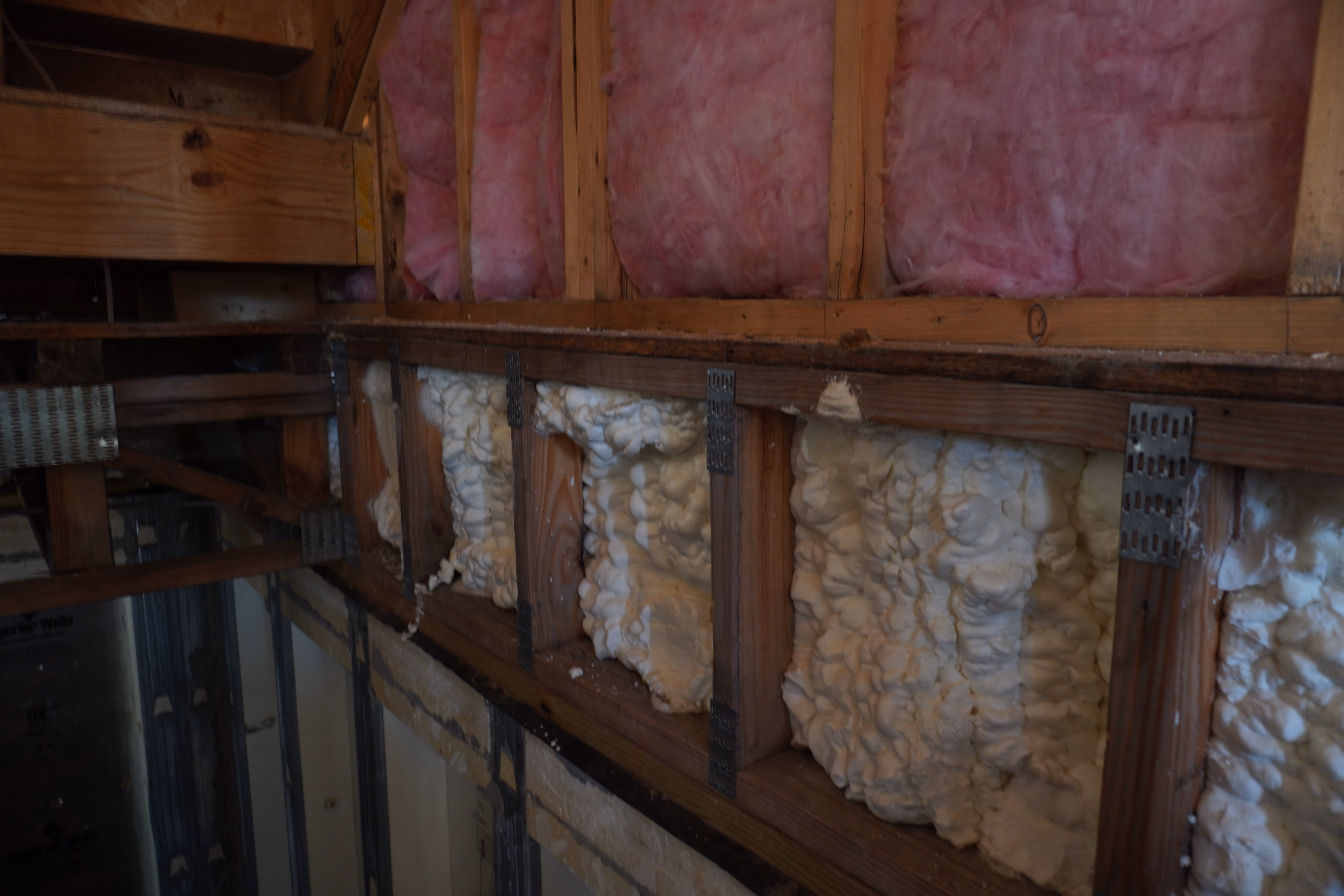 Spray foam application across multiple bays of exposed roof framing.