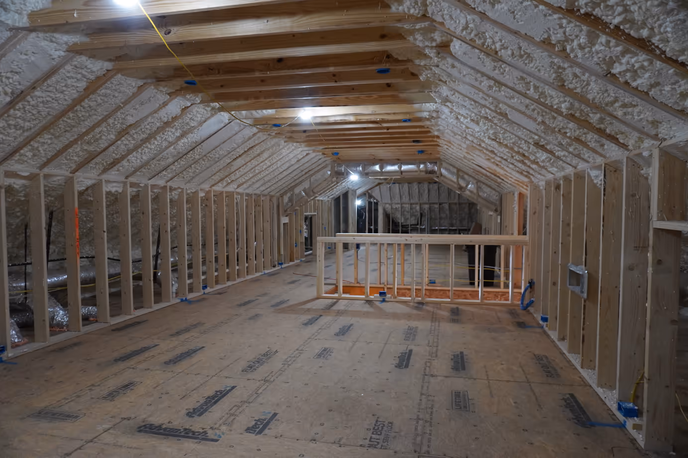 Wide attic view showing spray foam coverage across roof framing.
