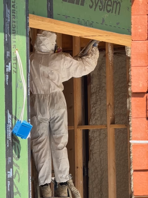 Installer applying spray foam to an open wall assembly.
